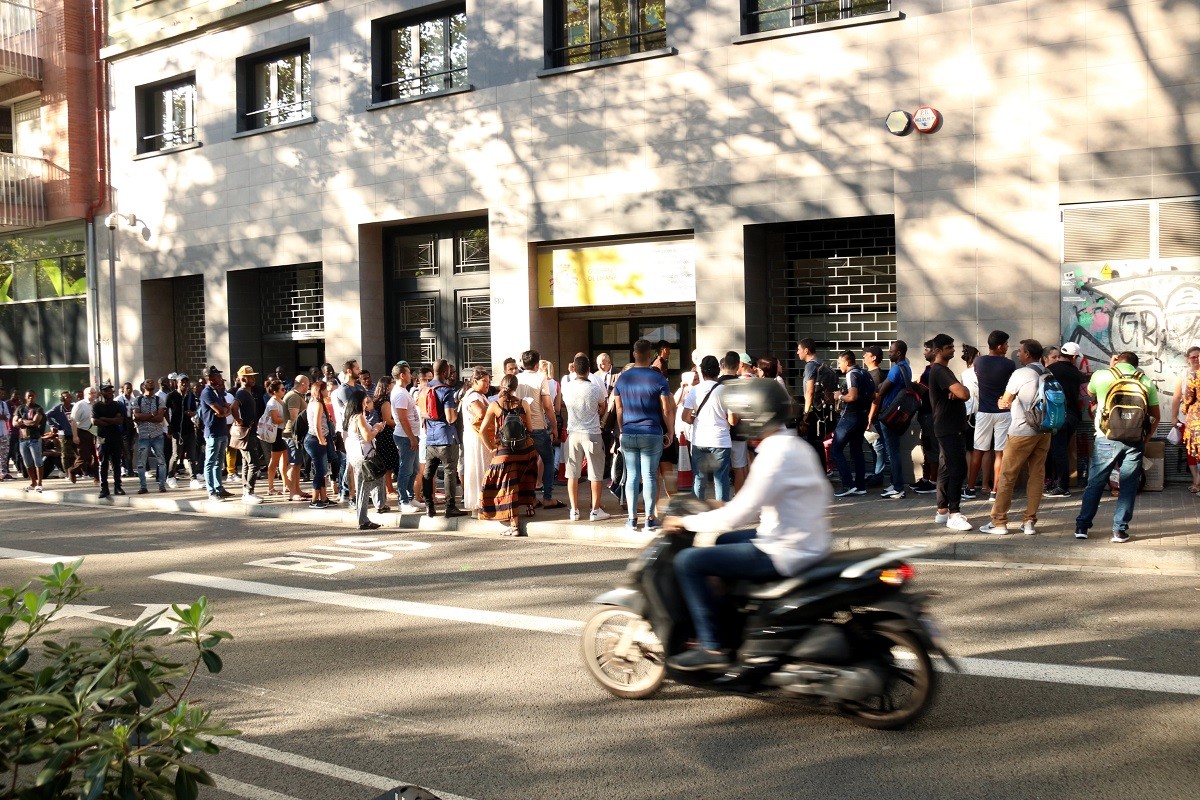 Desenes de persones fan cua a les portes de l'Oficina d'Estrangeria de Barcelona.