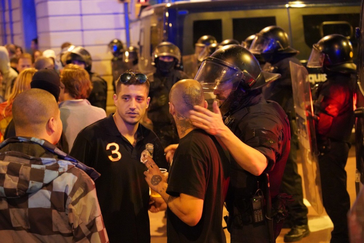 Un agent dels Mossos parlant amb dos ultres de Democracia Nacional a la plaça d'Artós de Sarrià