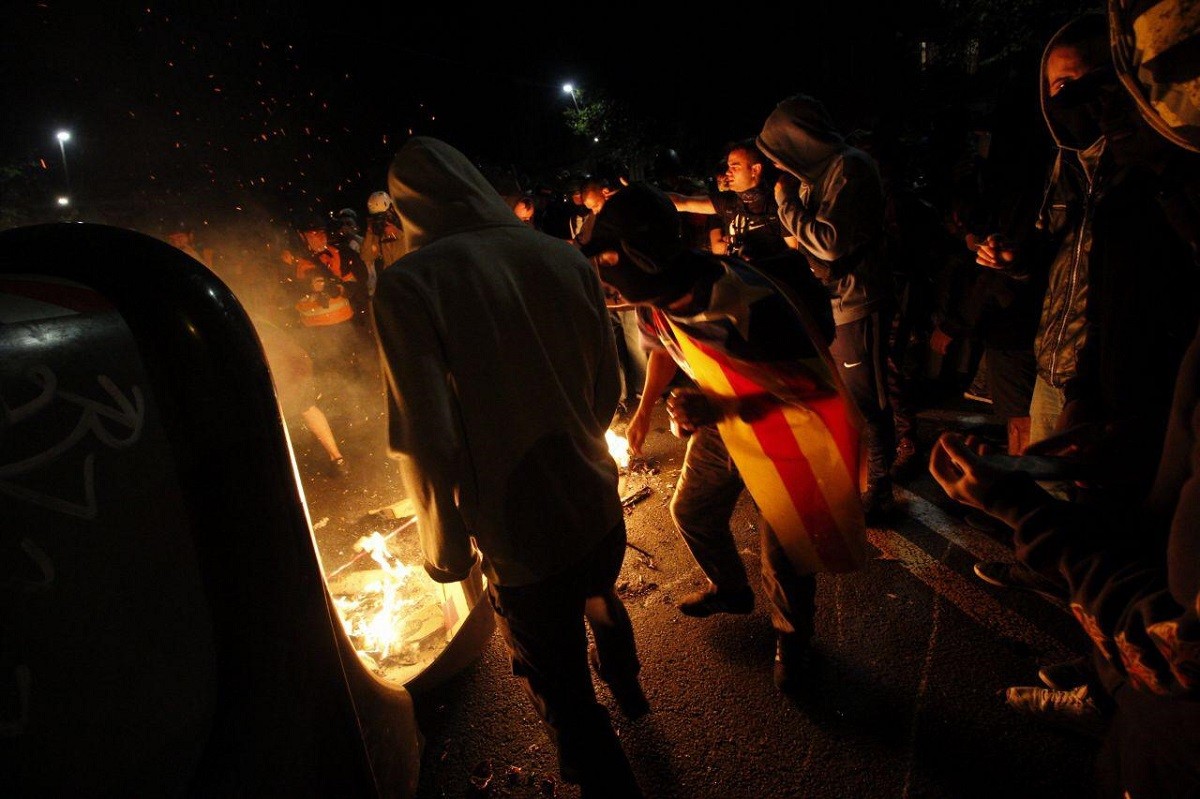 Manifestants, un d'ells amb el mòbil, aixecant una barricada a Barcelona.