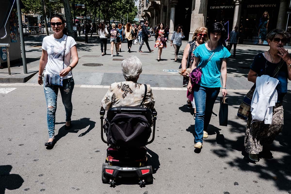 Una senyora amb cadira de rodes circulant pel passeig de Gràcia