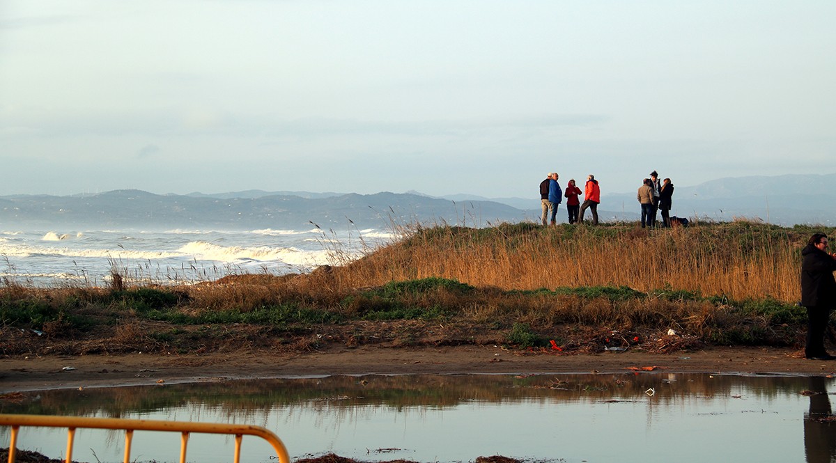 Un grup de curiosos observant els desperfectes que del temporal Gloria a la platja de la Marquesa, a Deltebre.