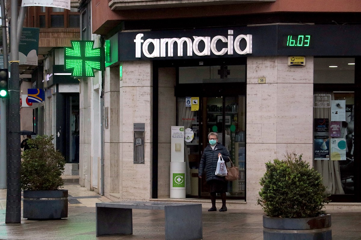 Una dona amb mascareta surt d'una farmàcia del centre de Tortosa.