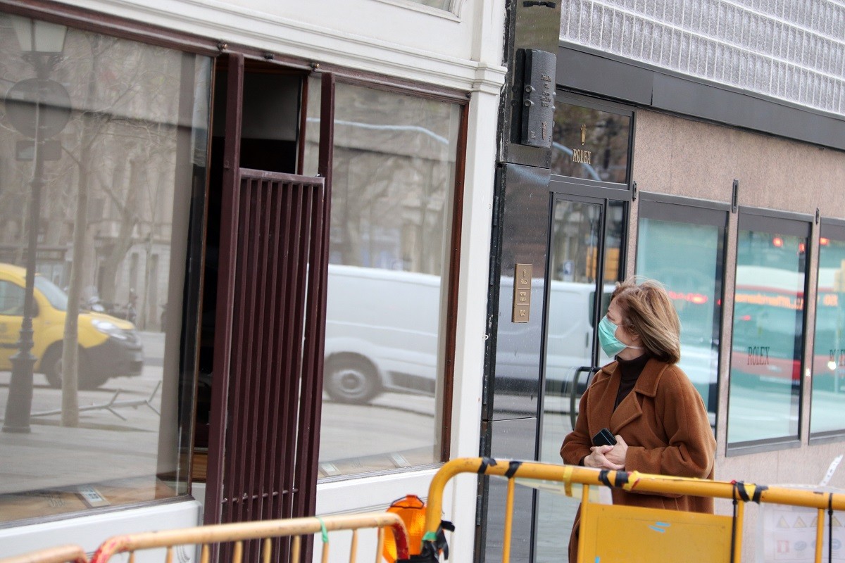 Una vianant amb mascareta observa botigues tancades al passeig de Gràcia