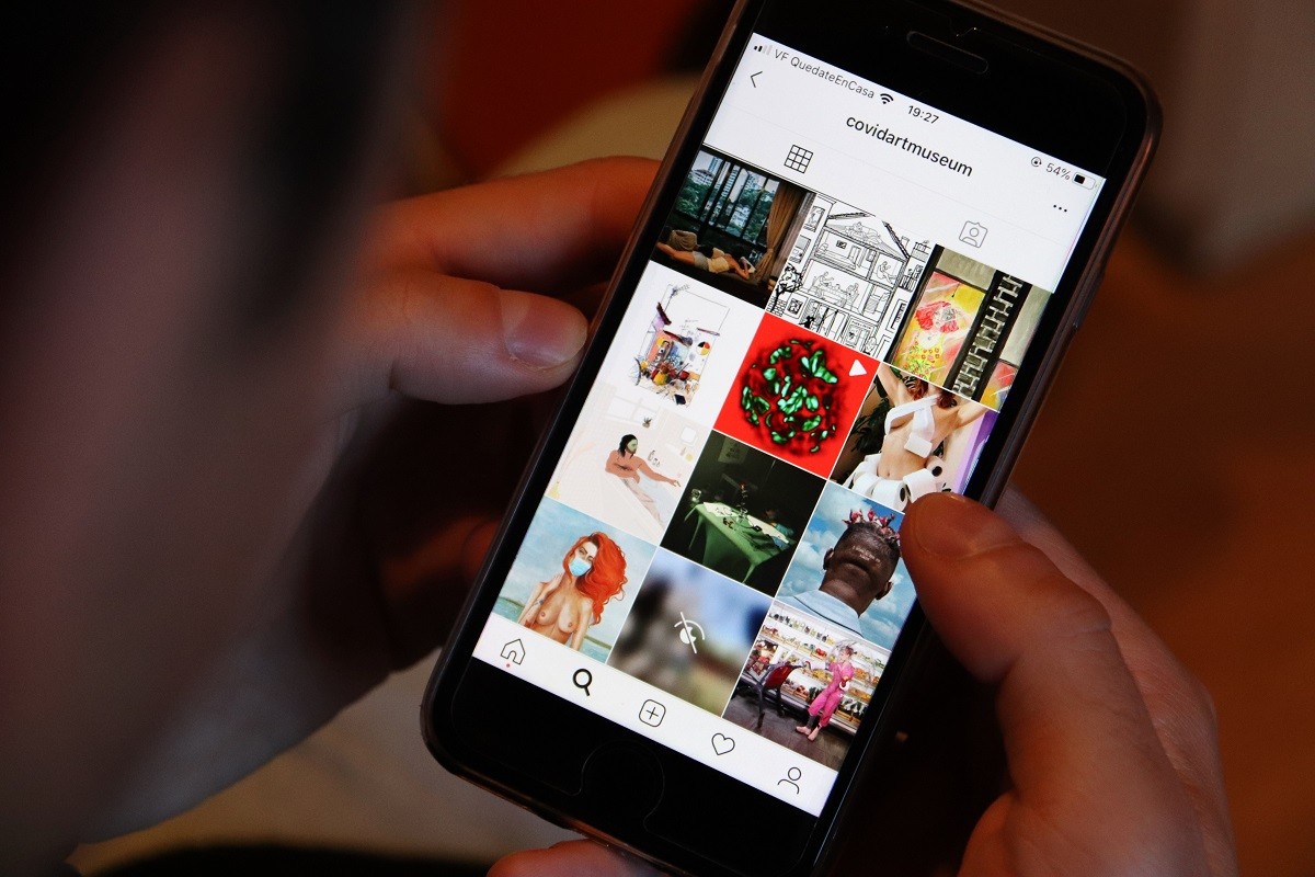 Una persona mira publicacions a Instagram de The Covid Art Museum.