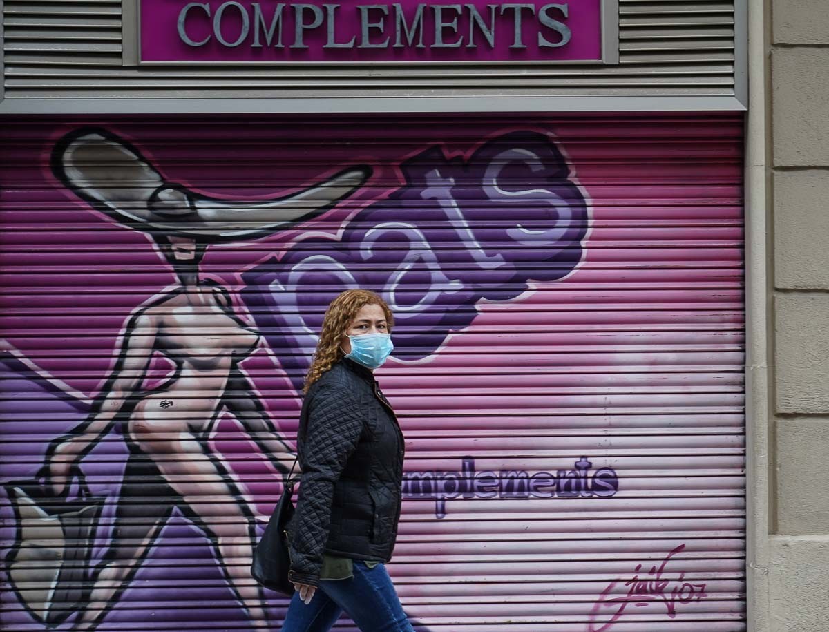 Una dona amb mascareta davant d'un comerç tancat