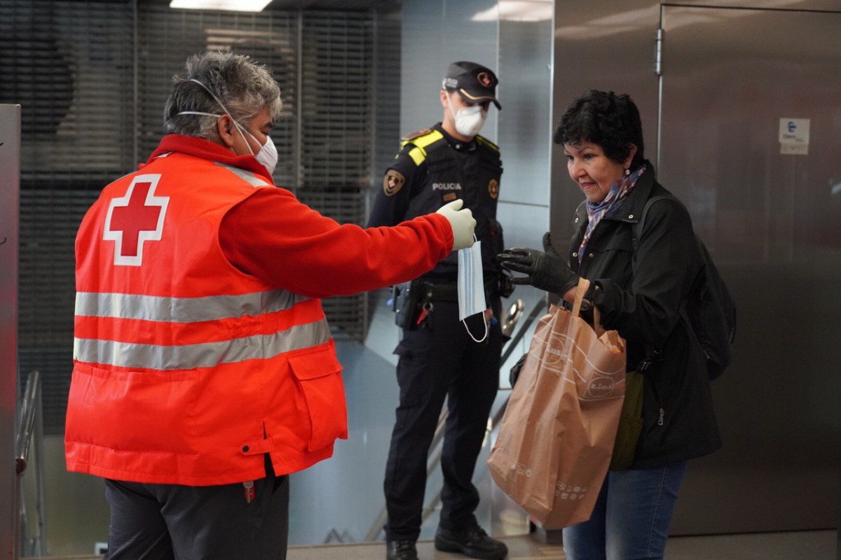 Un voluntari de la Creu Roja repartint mascaretes al metro
