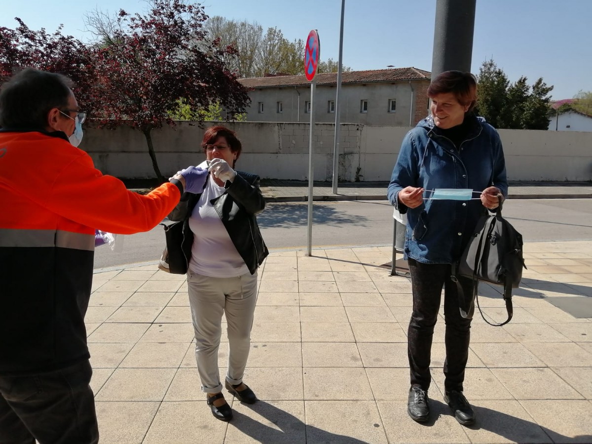 Uns voluntaris  liuren mascaretes als usuaris del transport públic d'Olot.