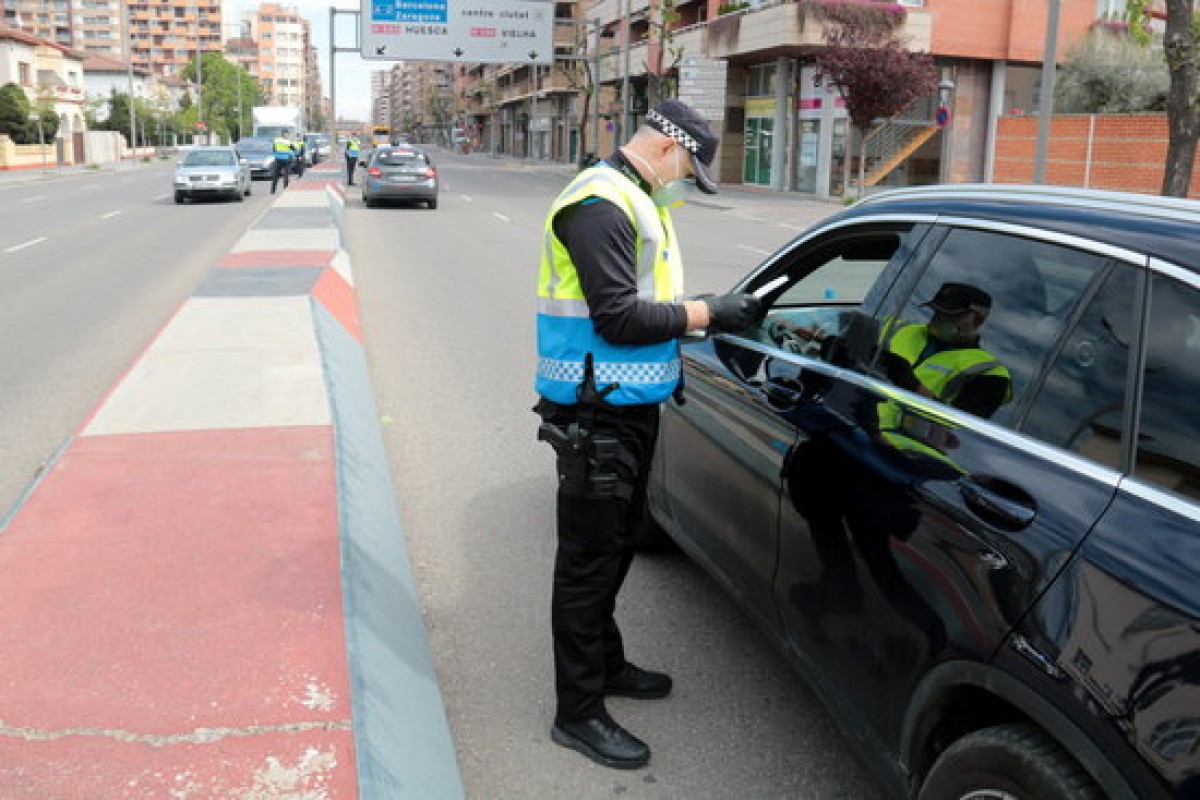 Un agent de la Guàrdia Urbana de Lleida parla amb el conductor d'un vehicle en un control per supervisar la mobilitat durant l'estat d'alarma