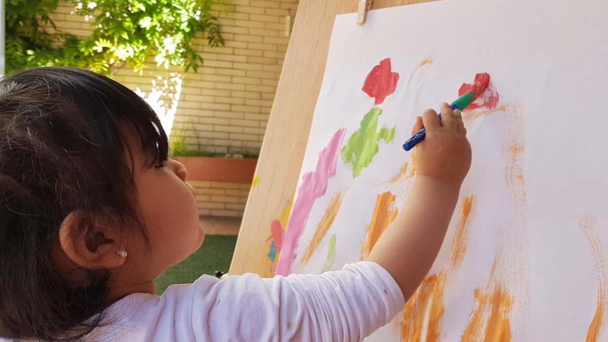 Una nena, pintant en una escola bressol 