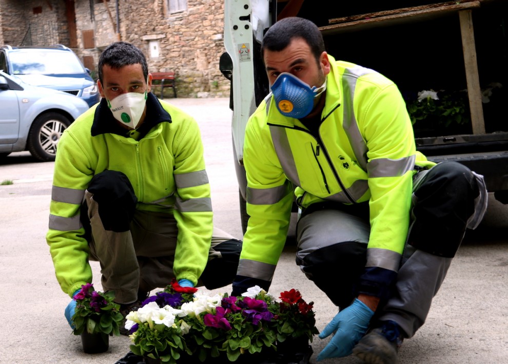 Dos operaris de l'Ajuntament de Sort amb les flors que repartiran entre els veïns