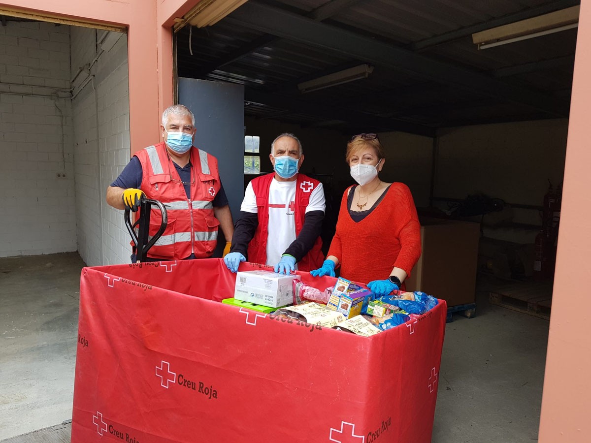 Les impulsores de la iniciativa amb voluntaris de Creu Roja en el moment del lliurament d'aliments solidaris