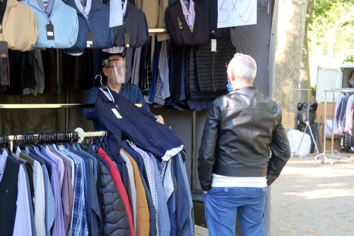 Un marxant ensenyan una peça de roba a un client al mercat de la Devesa de Girona.