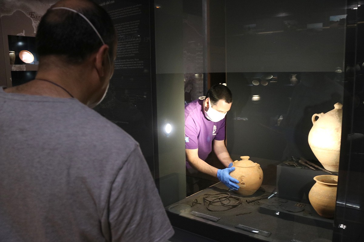 Treballadors del Museu de les Terres de l'Ebre retornant a la vitrina una peça ibèrica netejada
