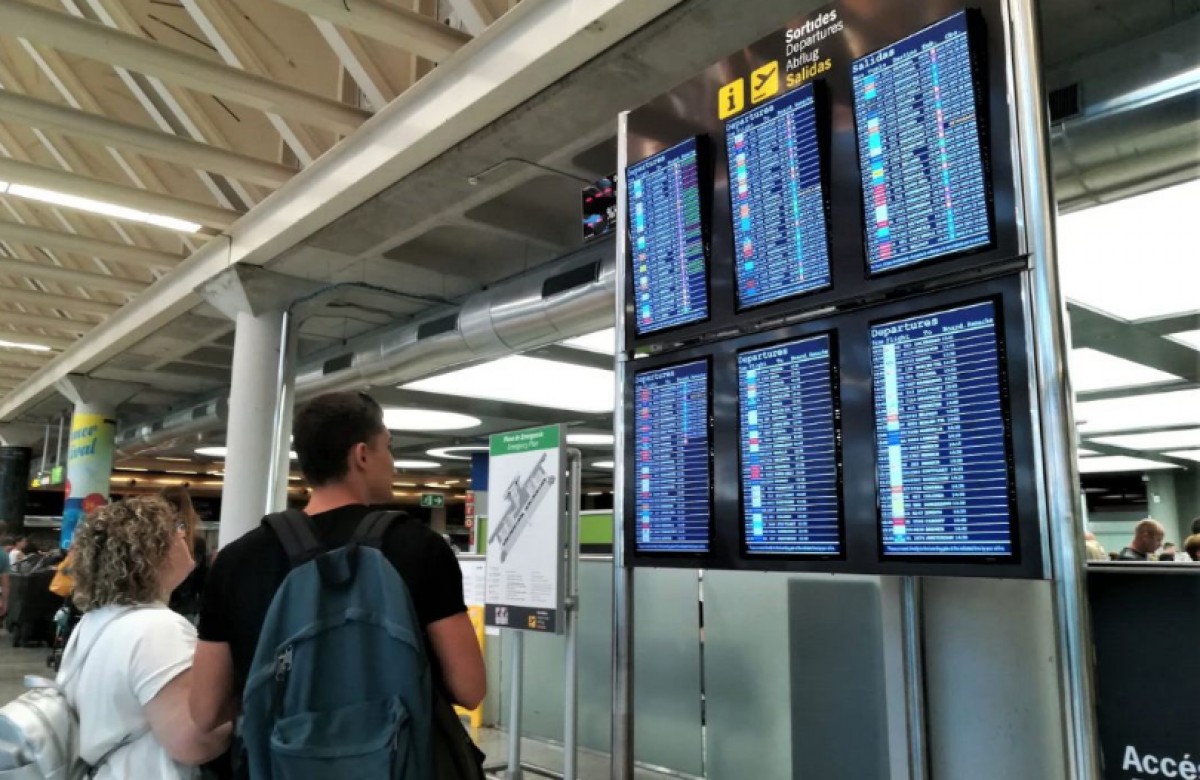 Dues persones consulten el seu vol a l'aeroport de Palma