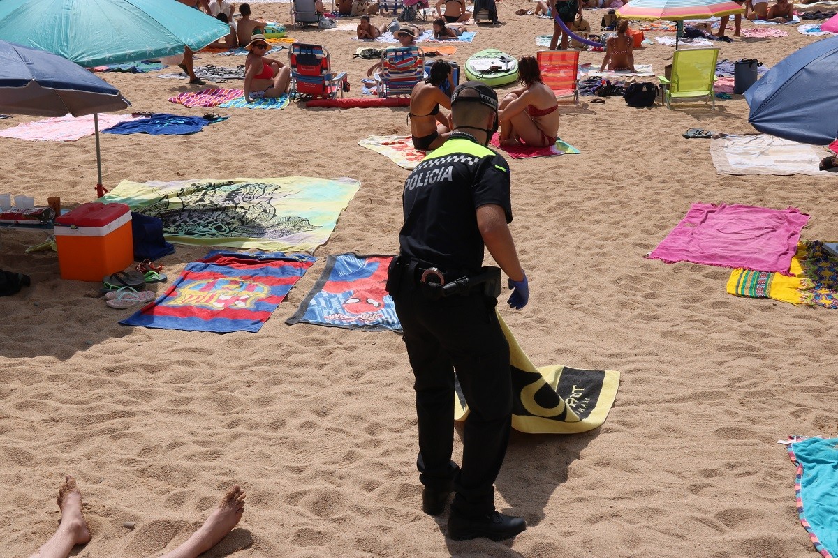 Imatge d'un agent retirant una tovallola sense propietari a la platja de Tamariu
