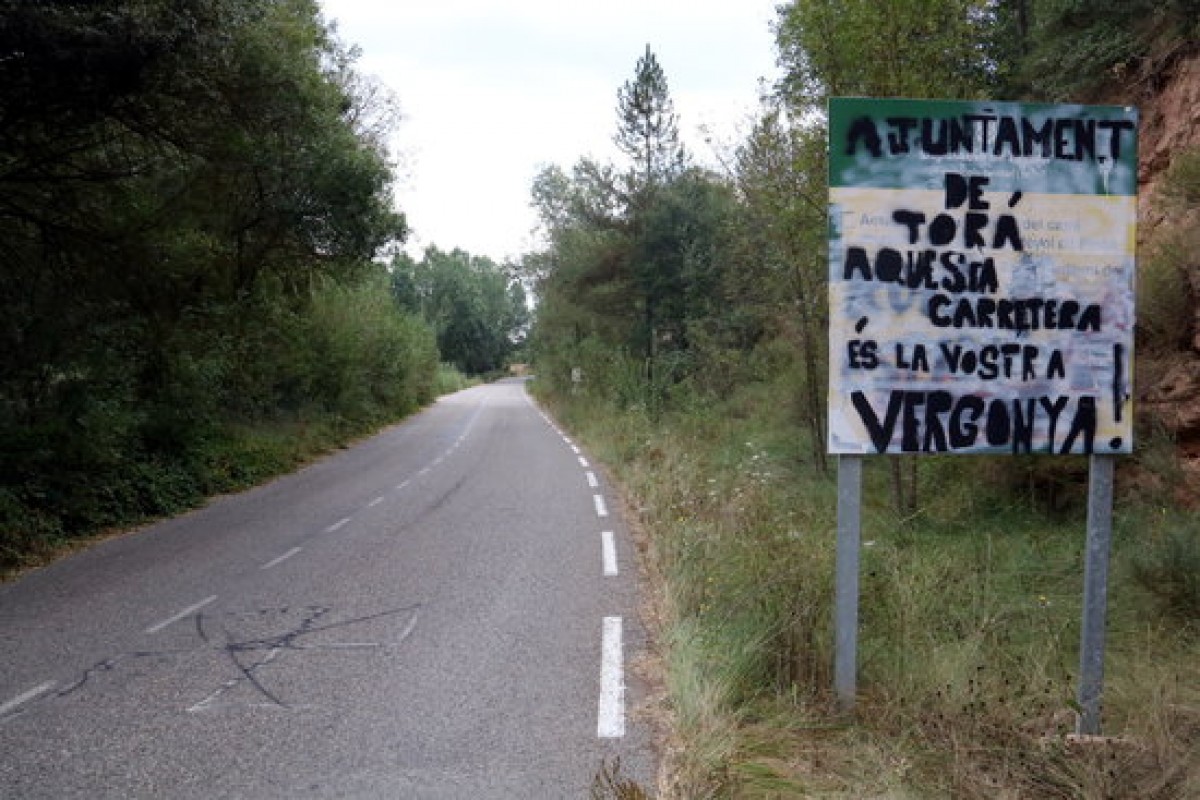 Un cartell on es llegeix 'Ajuntament de Torà, aquesta carretera és la vostra vergonya'.