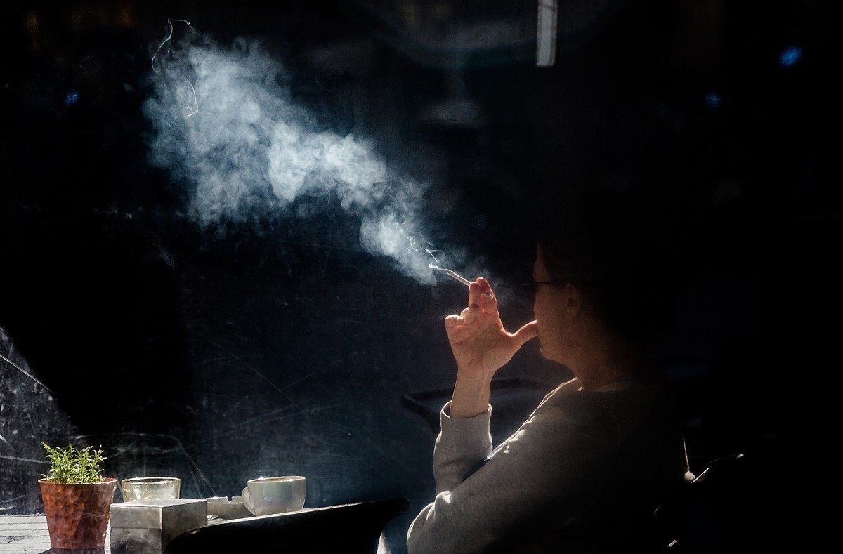 Una dona fuma a la terrassa d'una cafeteria