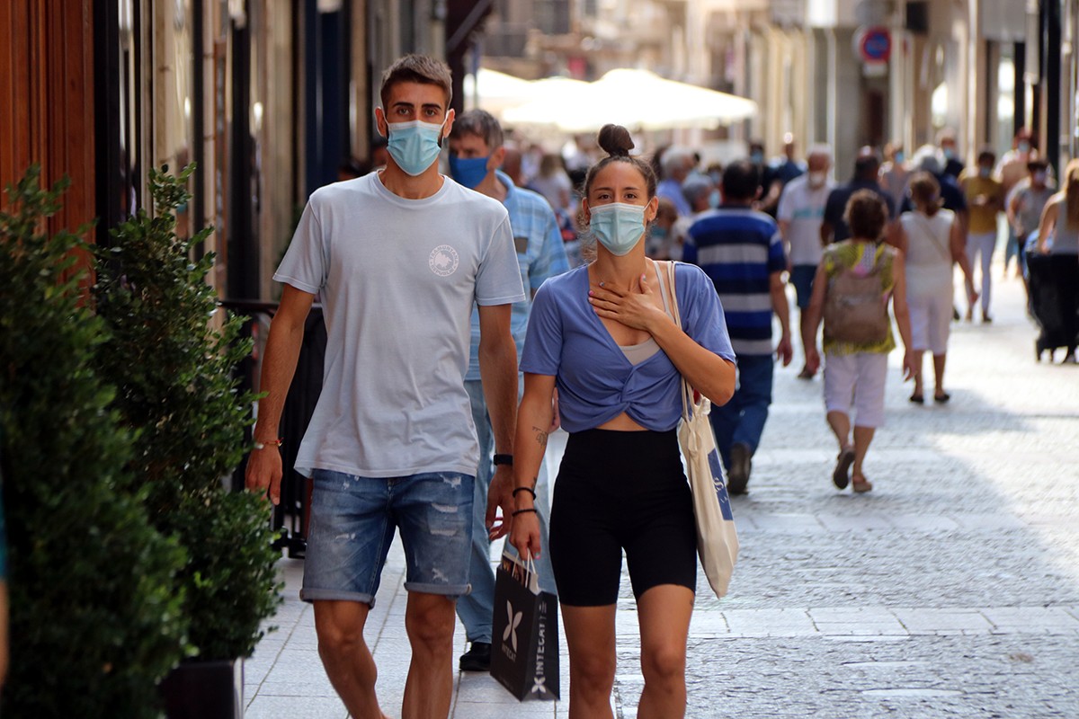Un noi i una noia caminant amb mascareta pel carrer Monterols de Reus.