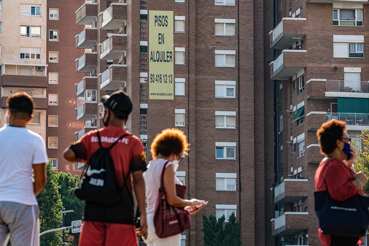 Una pancarta anuncia pisos de lloguer, davant ciutadans que passegen