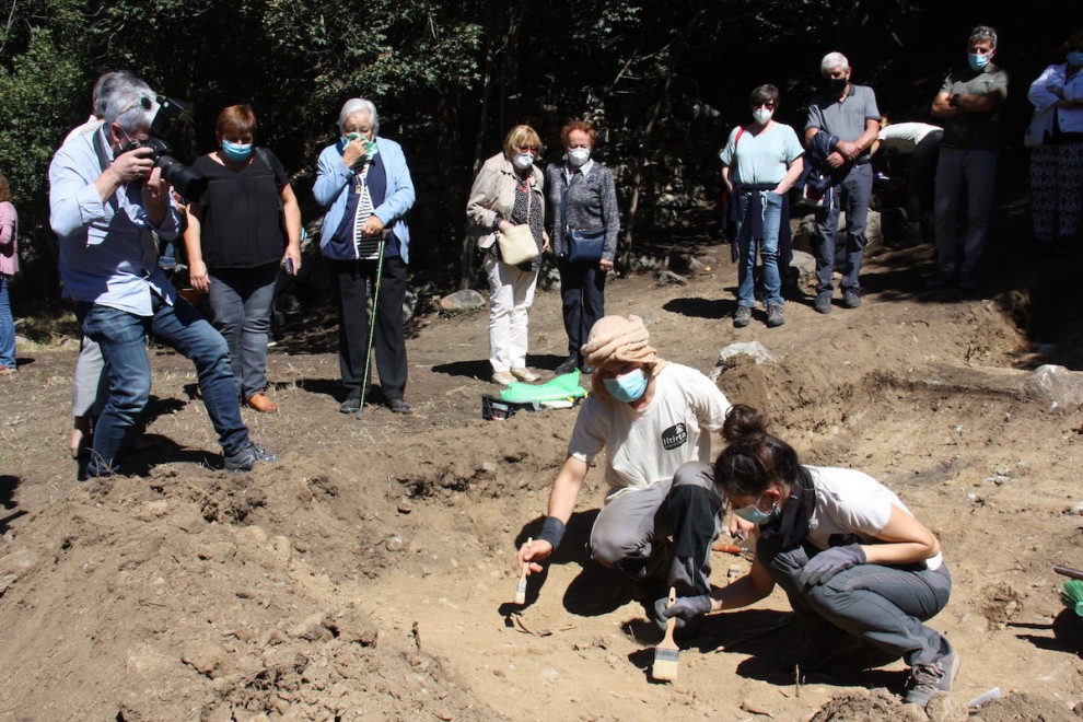 Arqueòlegs analitzant la fossa a Sorpe i familiars mirant-ho al darrere