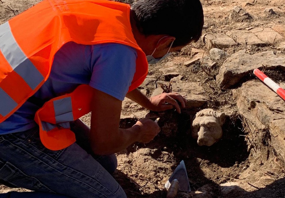 Un arqueòleg treballant en treure un cap de lleó de la vil·la romana de Llorís
