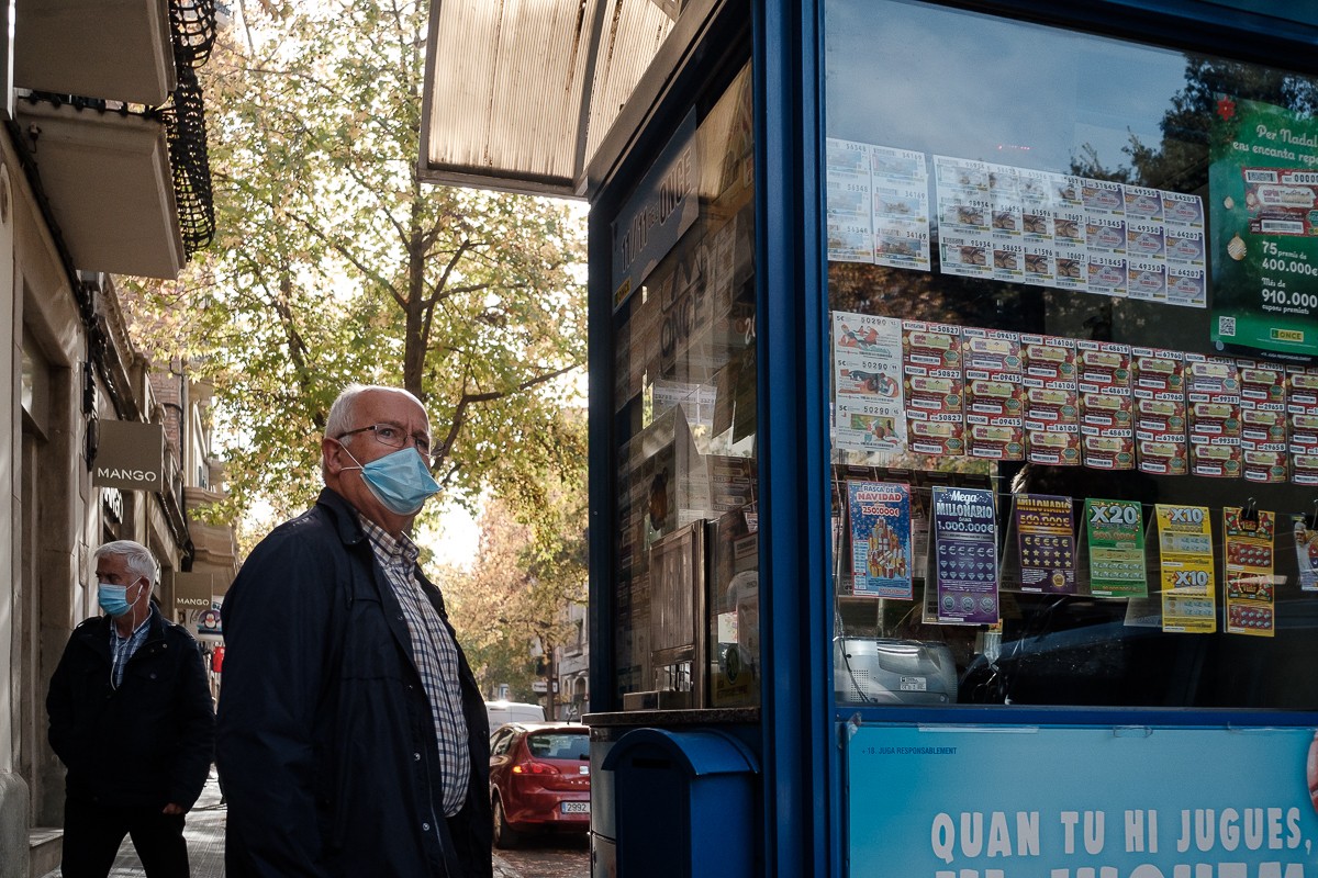 Un veí de Manresa amb mascareta davant d'una caseta de venda de loteria