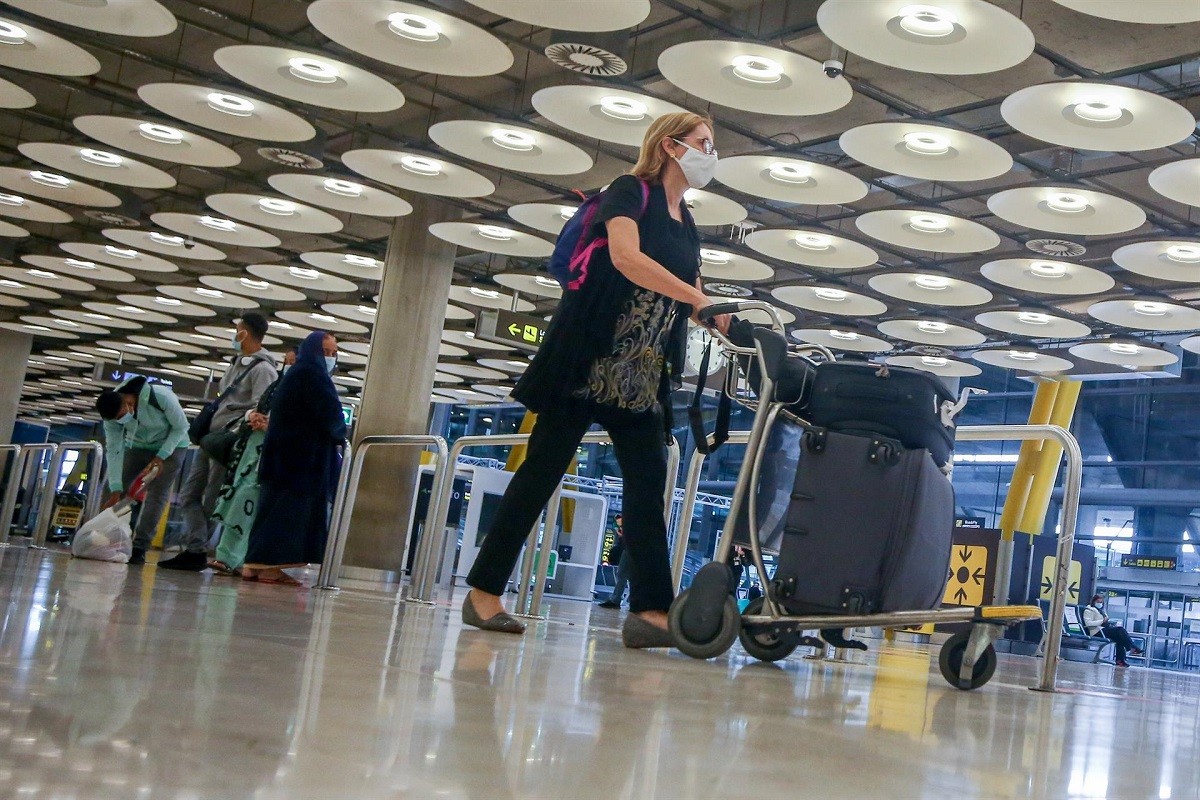 Una viatgera transporta l'equipatge en un aeroport.