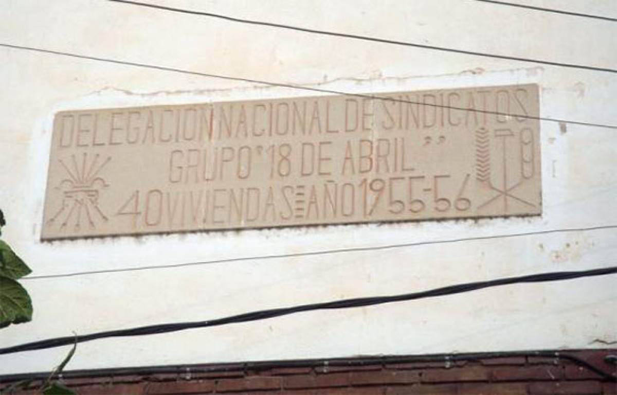 Placa de mosaic hidràulic rectangular on s'anuncia la construcció d'un grup d'habitatges de promoció oficial. 