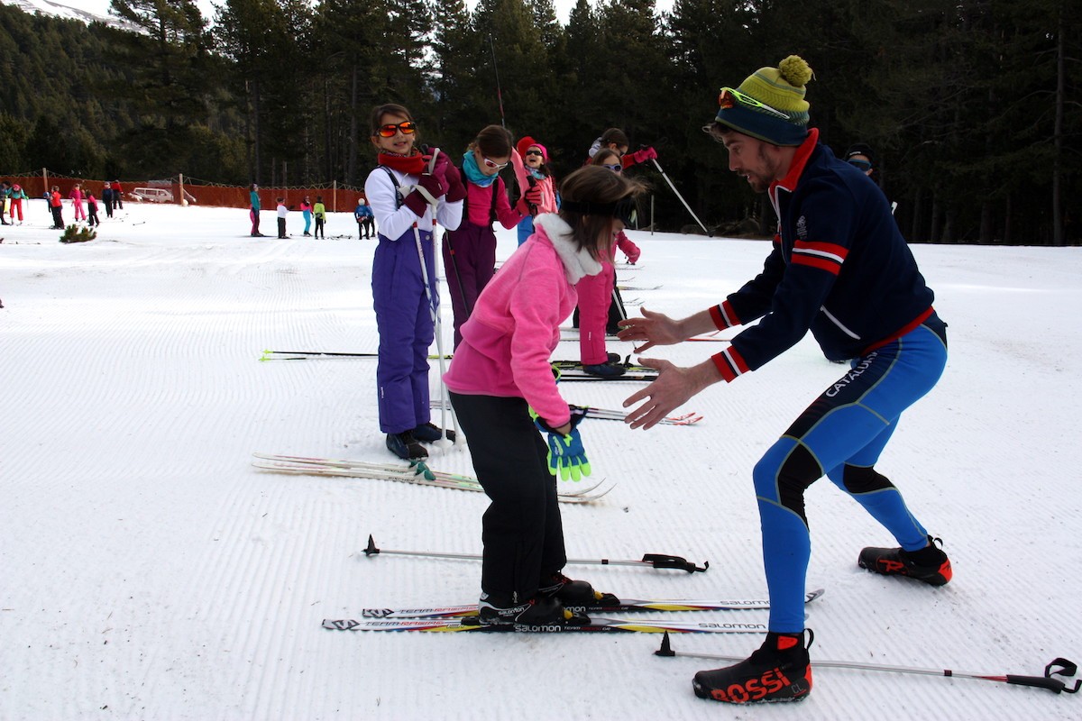 Un monitor ajudant una alumna a desplaçar-se amb els esquís