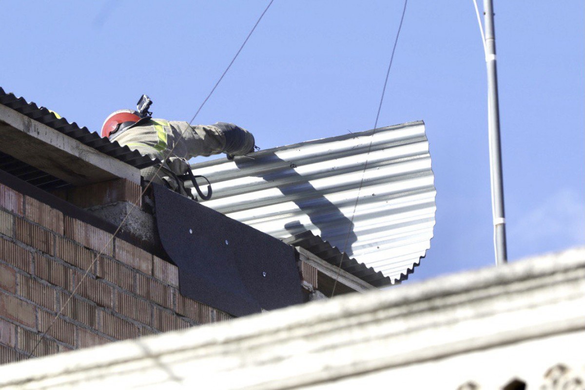 Un bomber treballant en una teulada afectada per ventades 