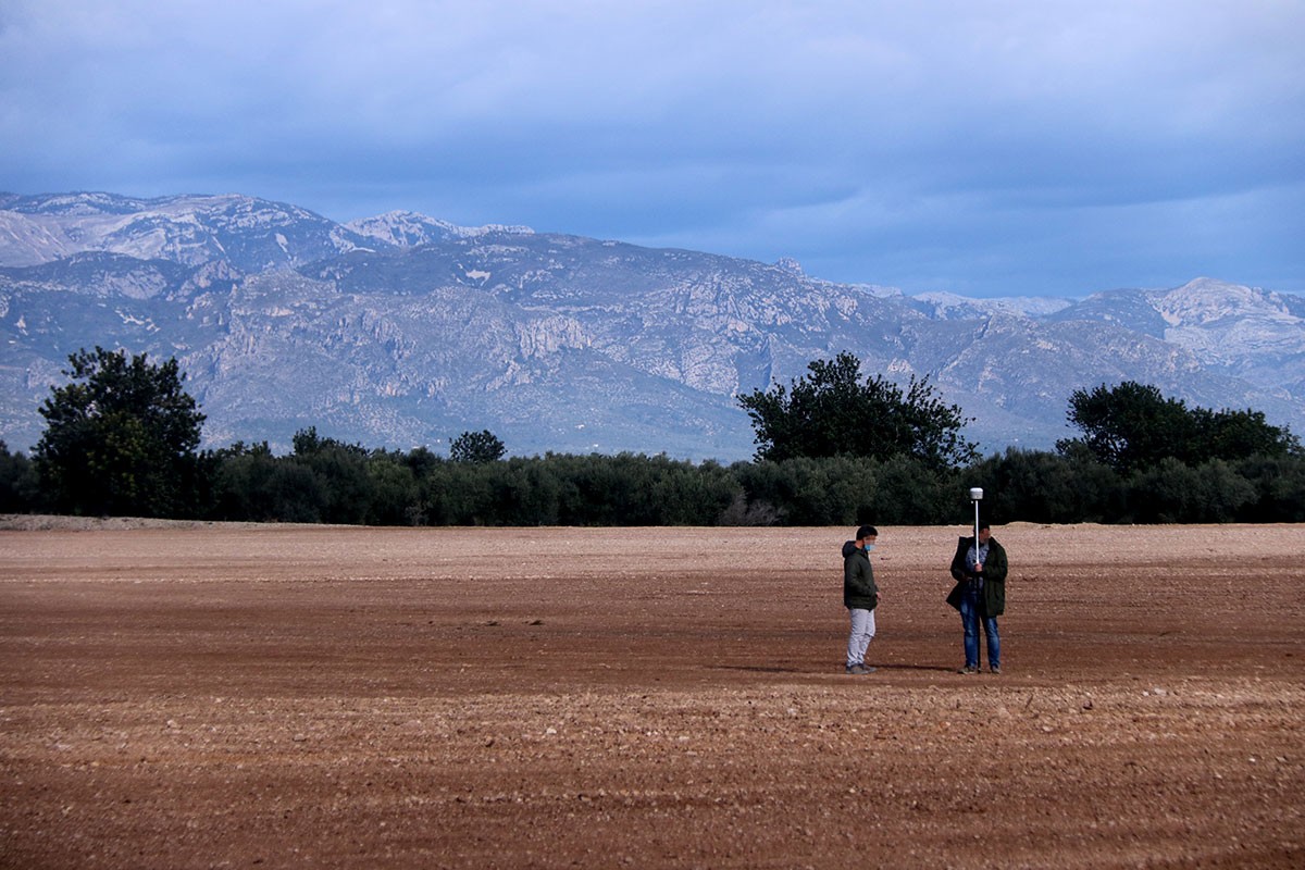 Els terrenys on es projecta la planta de compostatge a Santa Bàrbara amb dos persones prenent mesures del terreny.