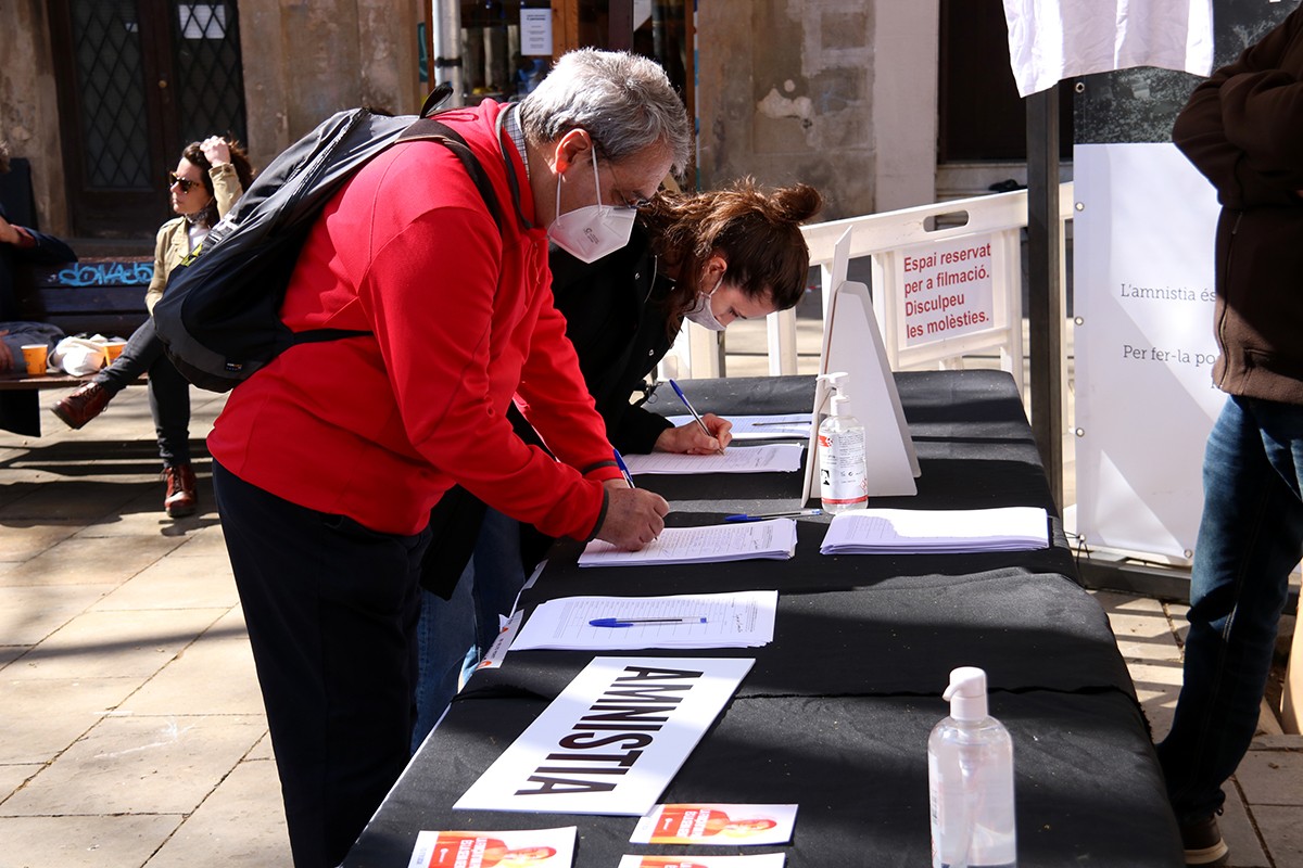 Dues persones signen a favor de la llei d'amnistia, en un acte d'Òmnium a Barcelona.