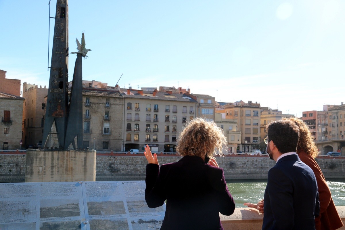 El vicepresident Pere Aragonès, la consellera de Justícia Ester Capella i l'alcaldessa de Tortosa Meritxell Roigé, d'esquenes, mirant el monument franquista des del passeig de l'Ebre.