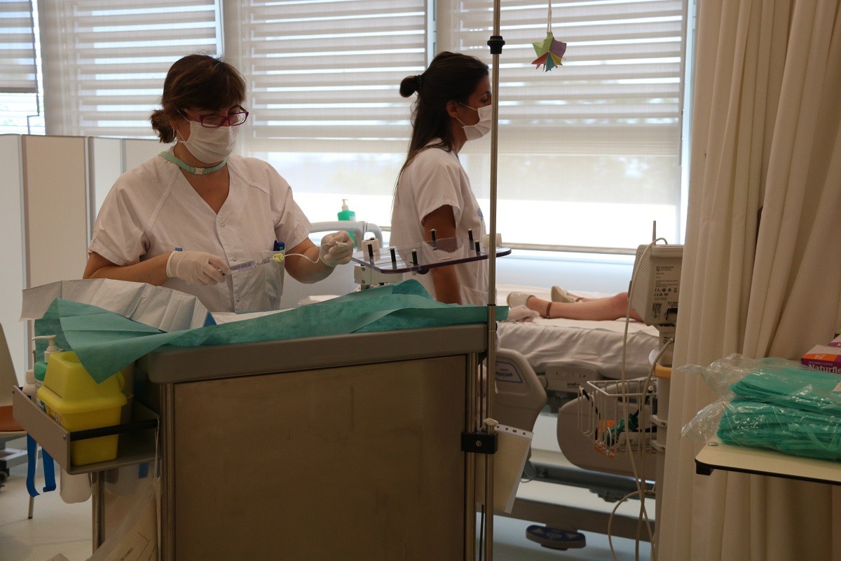 Dues infermeres atenent un nen fent tractament a l'Hospital de Dia de Vall d'Hebron.