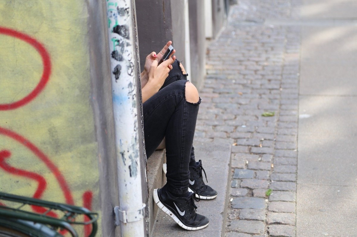 Una noia utilitzant el mòbil a peu de carrer