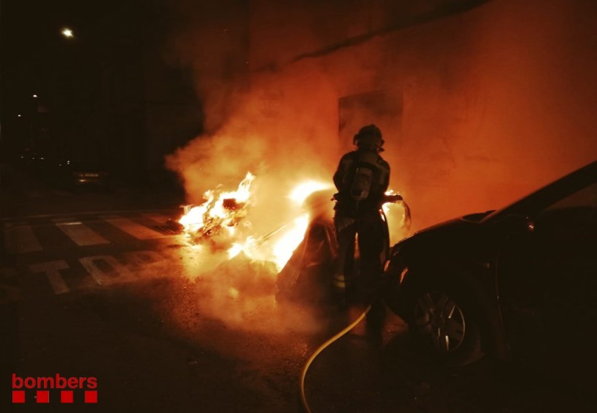 Un bomber apaga un contenidor en flames, en una imatge d'arxiu