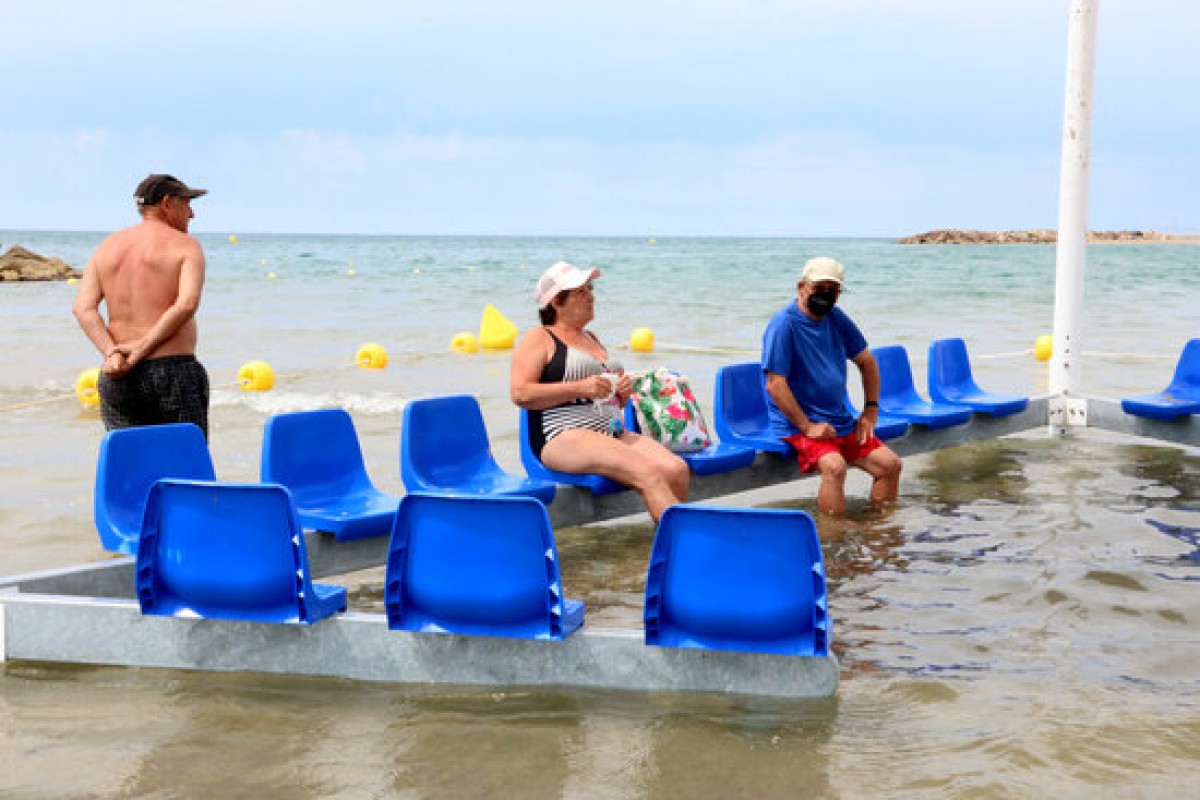 Tres banyistes utilitzant la nova àrea accessible per a persones amb mobilitat reduïda a la platja de Cunit