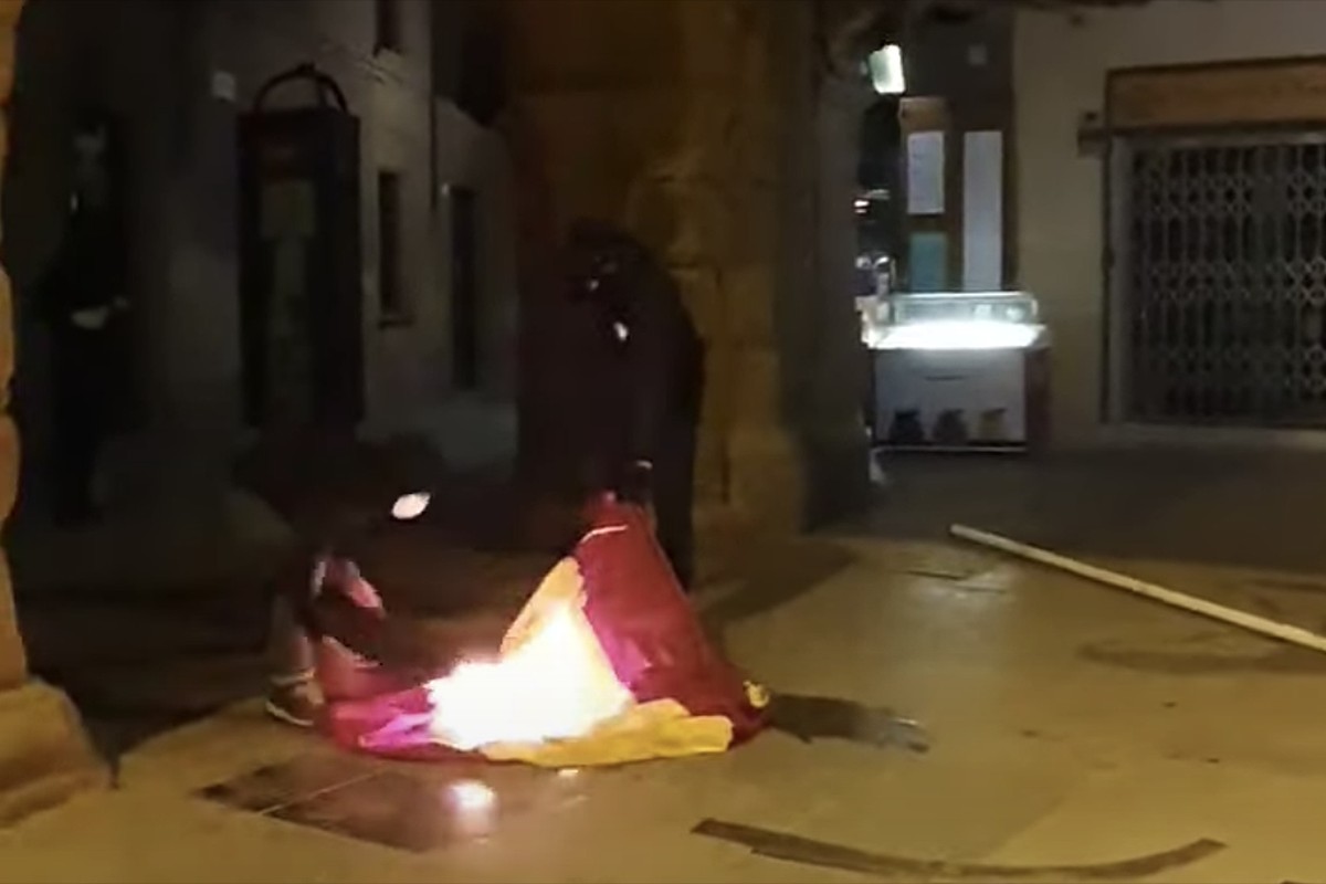 Dues persones cremant la bandera espanyola a la plaça de Vic