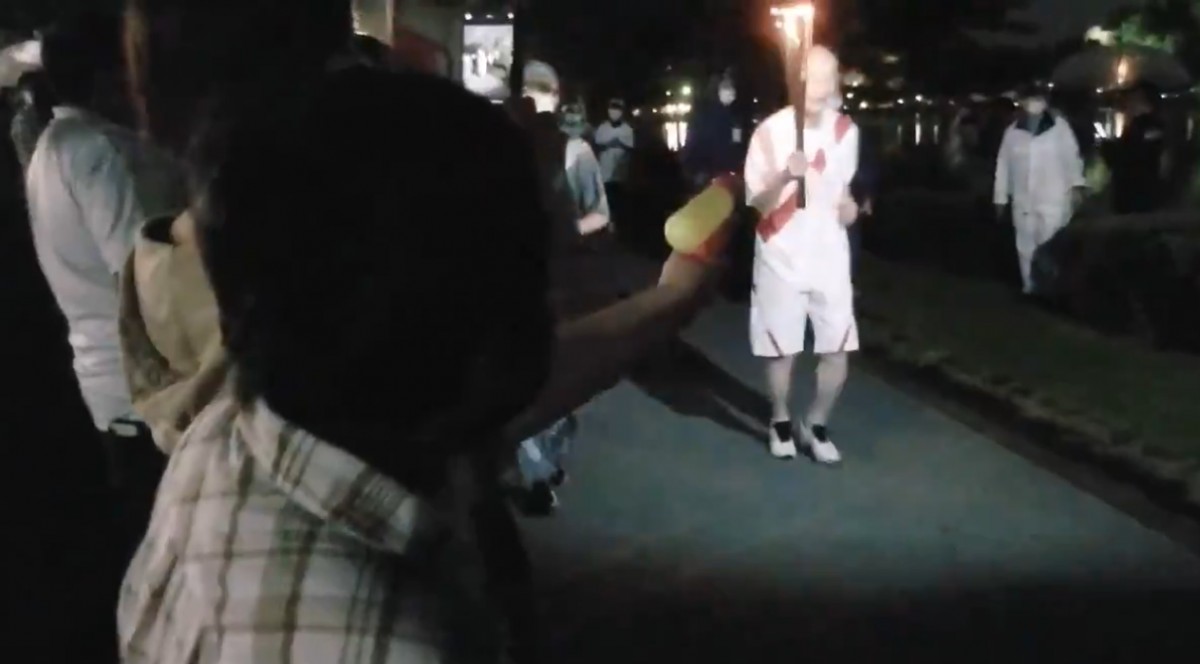 Una aficionada intenta apagar la torxa olímpica amb una pistola d'aigua