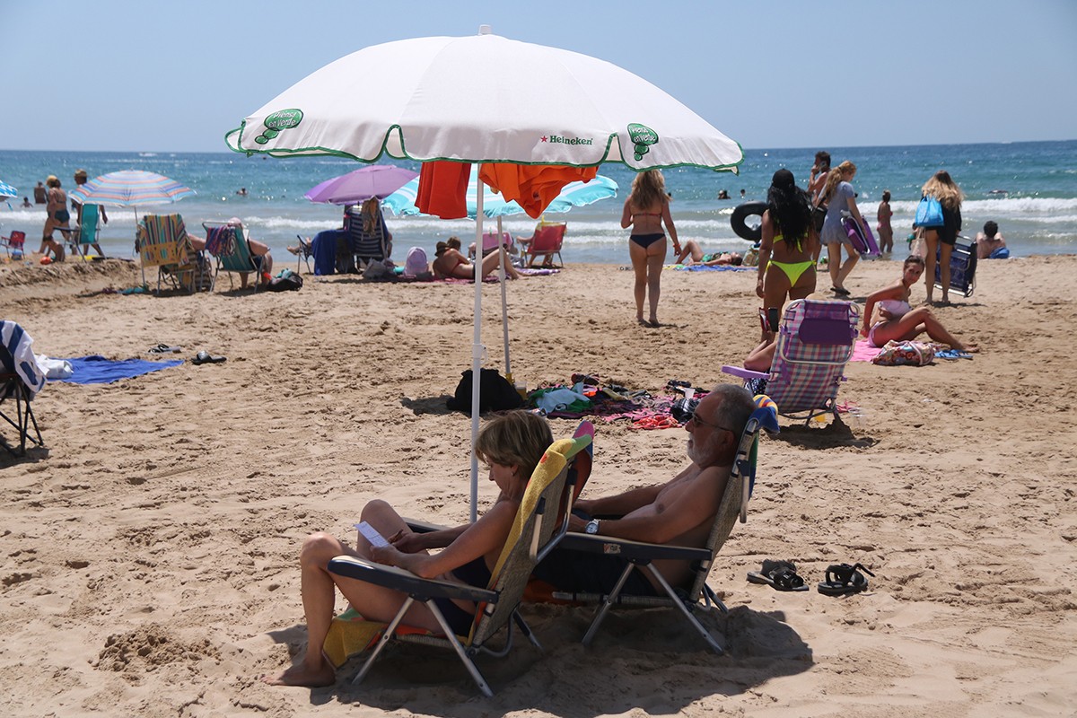 Dues persones sota una ombrel·la a la platja de Salou.