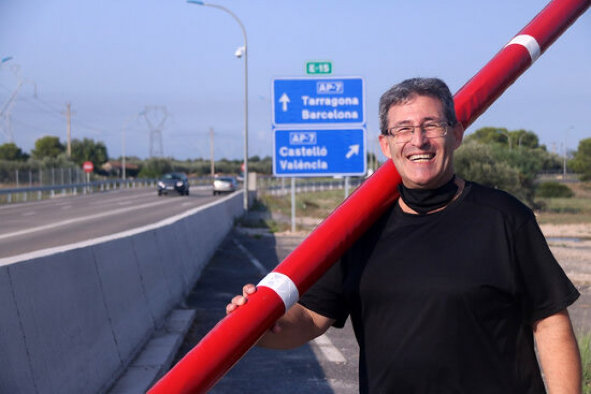 Pla mitjà de l'activista per l'alliberament de l'AP-7, Llorenç Navarro, amb una de les barreres al lloc on es trobava el peatge de l'Aldea. 