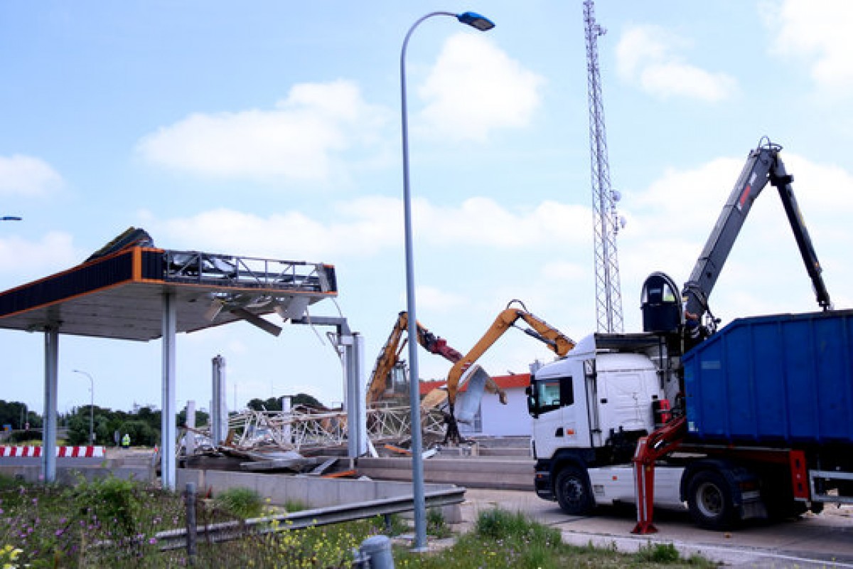 Camions i màquines treballant en les obres de retirada de les estructures del peatge de l'Aldea de l'AP-7