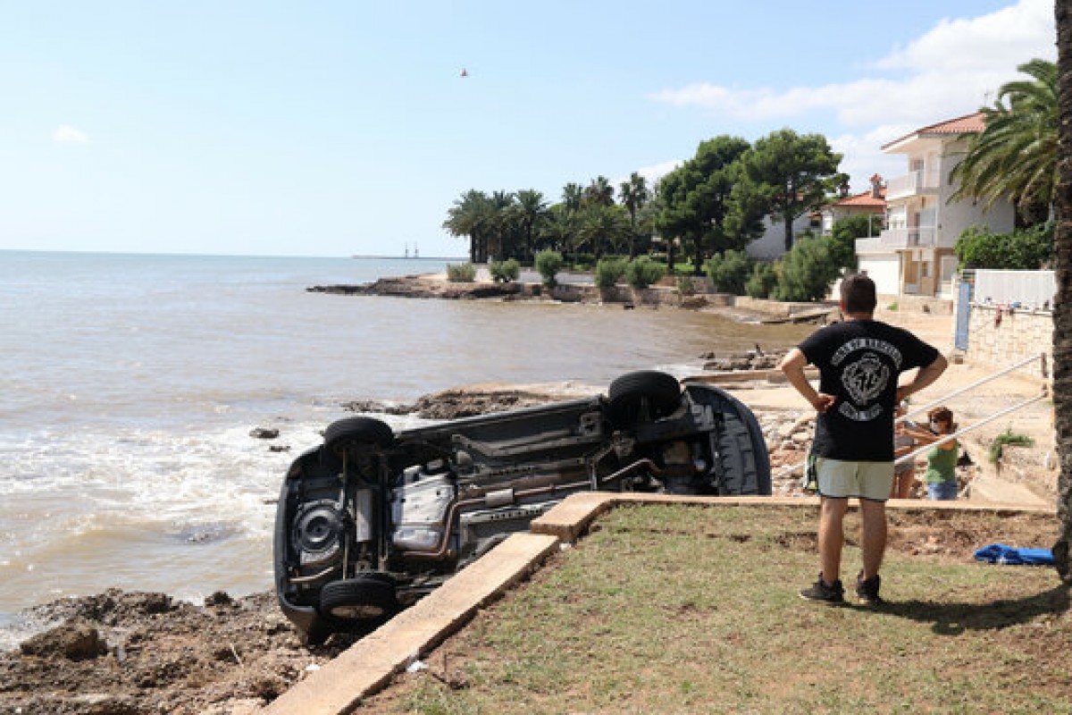 Pla sencer d'un home mirant-se un dels cotxes del Càmping Alfacs que va acabar al mar. 