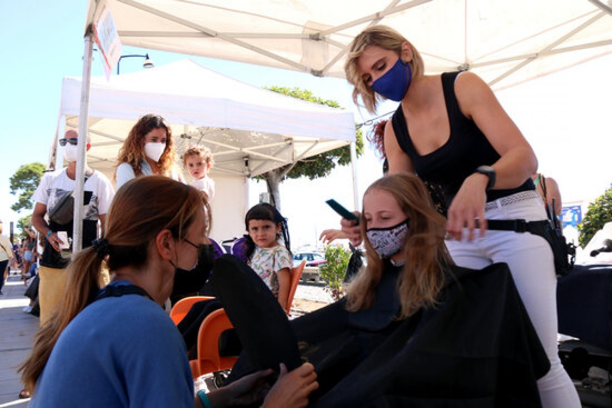 Una perruquera pentinant el cabell d’una nena en la cinquena edició de la campanya “Deixa’t prendre el pèl” a Cambrils
