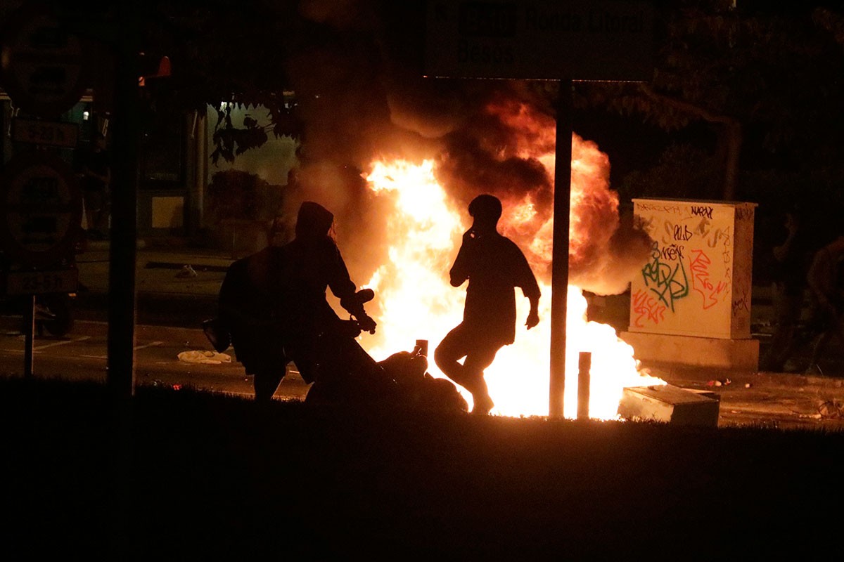 Dos joves, cremant una moto en el macrobotellot de plaça Espanya