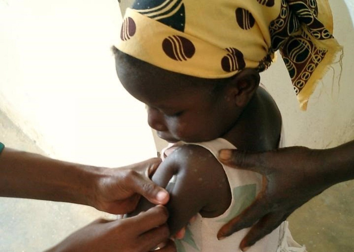 Una nena es vacuna contra la malària a un centre de salut de Moçambic