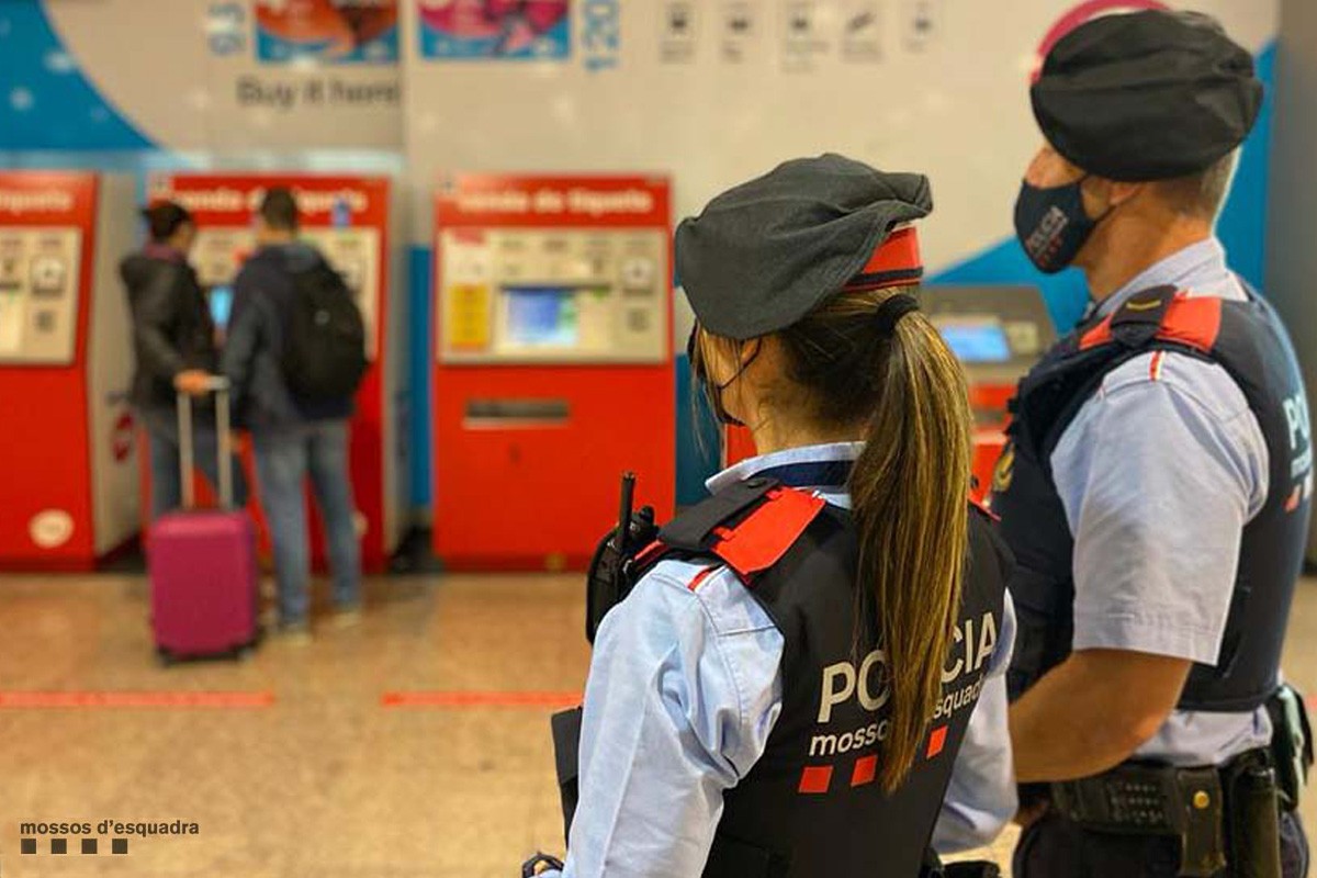 Dos agents dels Mossos d'Esquadra a una estació del Metro de Barcelona, amb les màquines expenedores de bitllets al fons