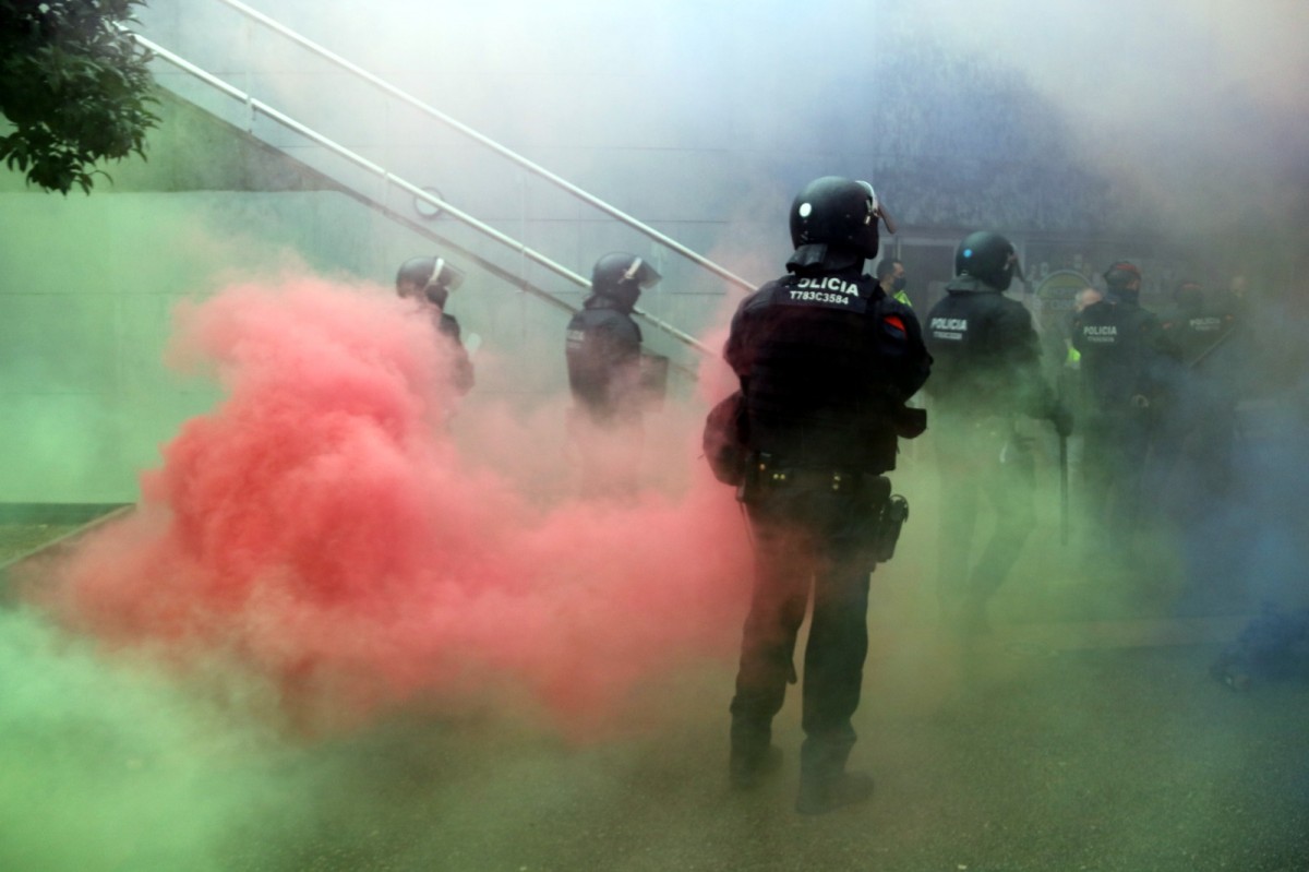 Imatge d'un agent dels mossos entre pots de fum de colors 