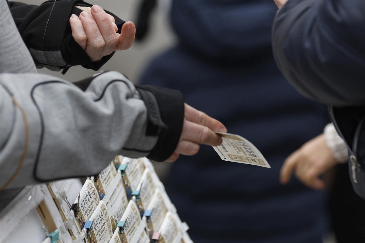 Una venedora lliura una butlleta de la loteria de Nadal