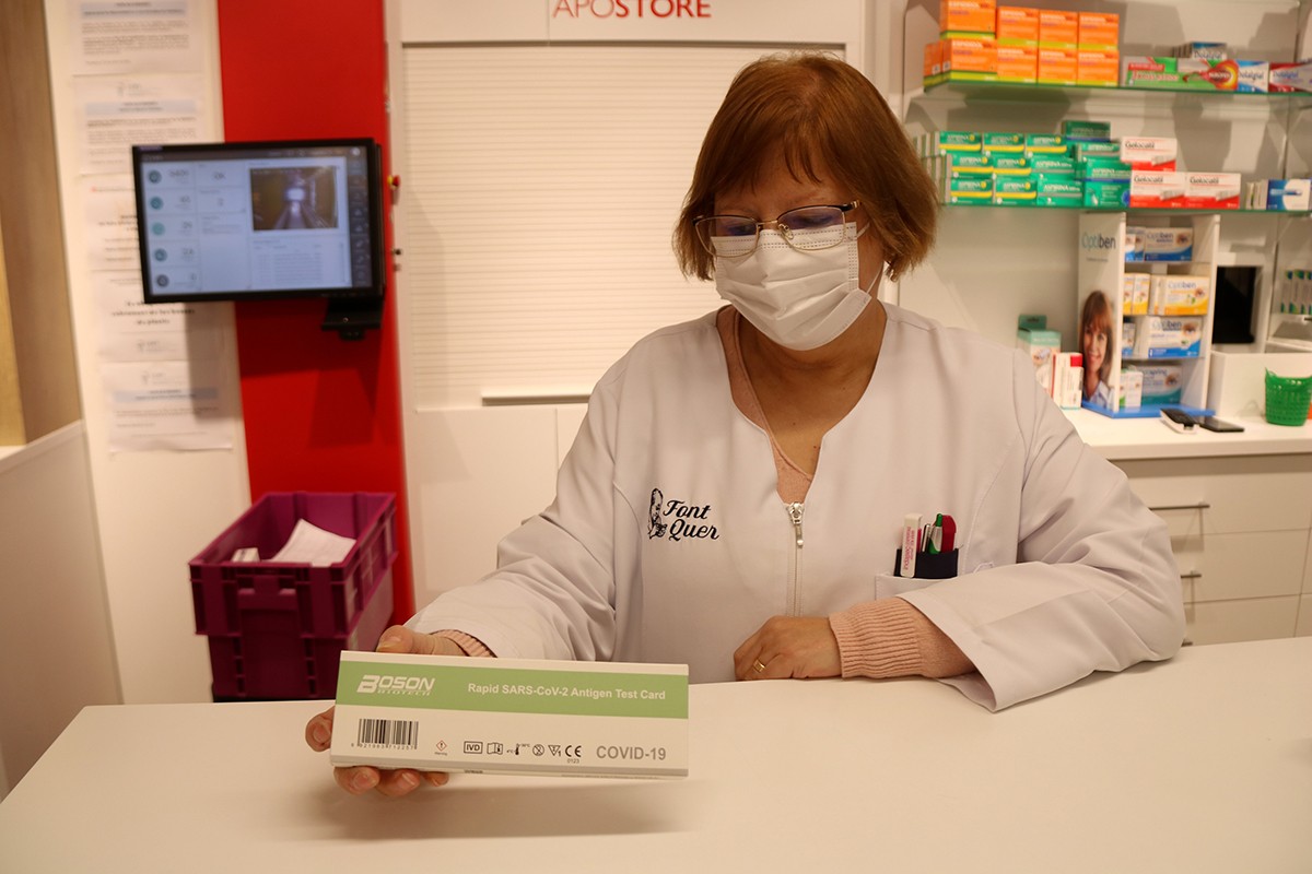 Una farmacèutica subjectant una caixa d'un test d'antigen en una farmàcia